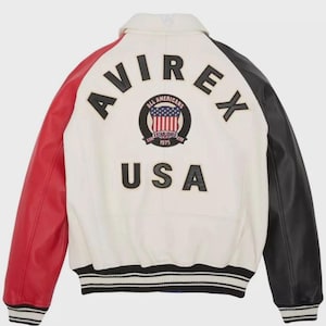 May include: A white leather jacket with red and black sleeves. The back features the word "AVIREX" above a circular emblem and the word "USA". The emblem includes the text "ALL AMERICANS ESTABLISHED 1975".