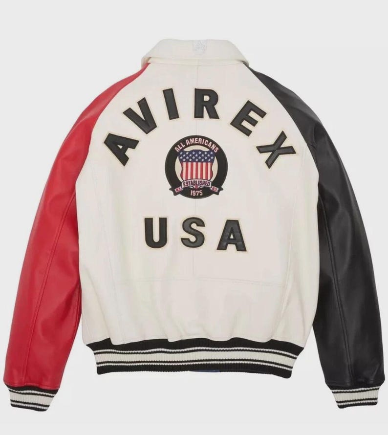 May include: A white leather jacket with red and black sleeves. The back features the word "AVIREX" above a circular emblem and the word "USA". The emblem includes the text "ALL AMERICANS ESTABLISHED 1975".