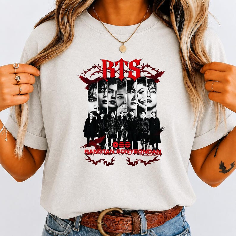 May include: A light gray t-shirt featuring a graphic print with the text BTS and BANGTAN SONYEONDAN. The design includes black and white portraits of seven individuals arranged in vertical panels, surrounded by red barbed wire and bird motifs.
