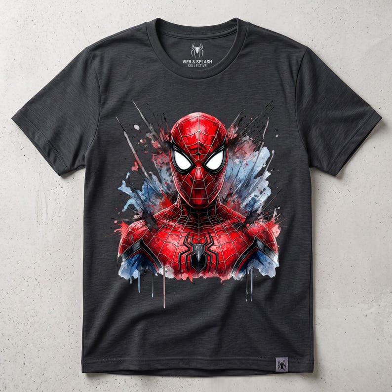 May include: A charcoal gray short-sleeve t-shirt featuring a vibrant red and blue watercolor-style graphic of a masked superhero on the chest. The inner neck label displays the text Web & Splash Collective with a small spider icon.