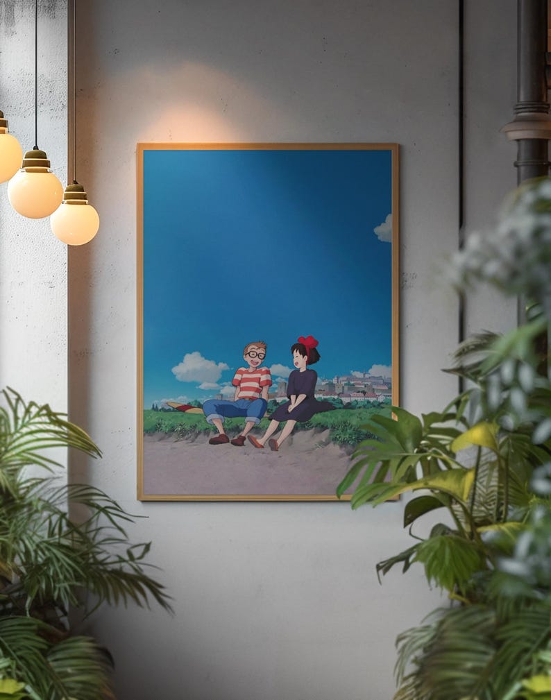 May include: A framed print featuring an anime-style illustration of two figures sitting on a grassy hill under a blue sky with clouds. One figure wears glasses and a striped shirt, the other a black dress and red bow.