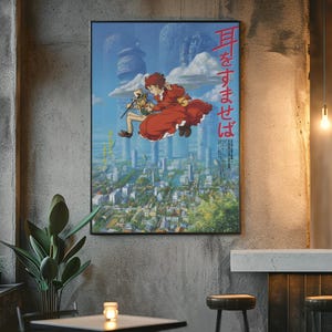 May include: A framed poster featuring anime artwork. The image shows two characters floating above a cityscape. One character wears a red dress. Japanese text is visible on the poster. The poster is displayed on a concrete wall.