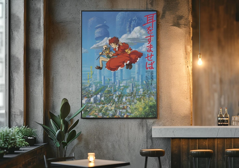 May include: A framed poster featuring anime artwork. The image shows two characters floating above a cityscape. One character wears a red dress. Japanese text is visible on the poster. The poster is displayed on a concrete wall.