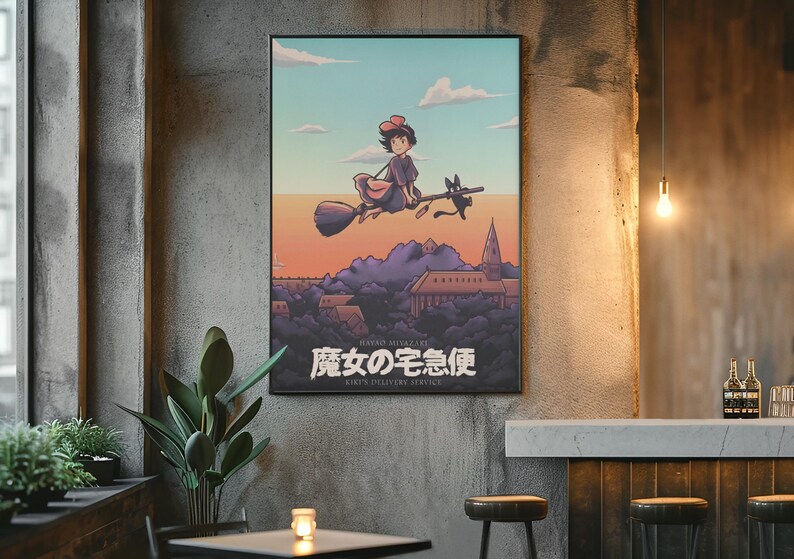 Op de afbeelding: Een rechthoekige wandposter met een geanimeerde illustratie van een jong persoon met een rode strik die op een bezemsteel vliegt met een zwarte kat. Daaronder ligt een stad met paarse heuvels en de Japanse tekst 魔女の宅急便.
