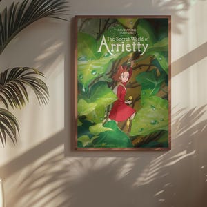 Pu&ograve; includere: Un poster incorniciato di "Arrietty - Il mondo segreto sotto il pavimento" con una ragazza in abito rosso in mezzo a un rigoglioso fogliame verde. Il poster &egrave; in una cornice di legno, appeso a una parete beige.