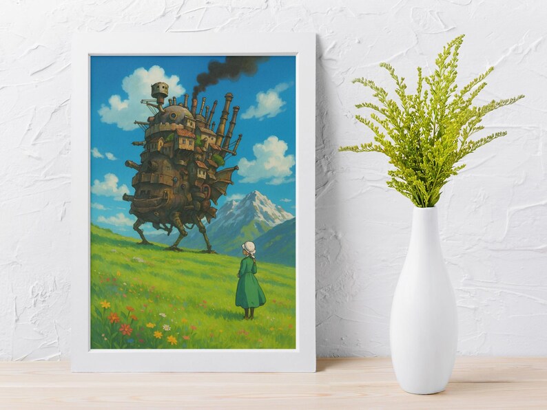 May include: A framed art print featuring a scene from the animated film "Howl's Moving Castle." The artwork depicts a large, walking castle on a grassy hill, a figure in a green dress, and a mountain range under a blue sky with clouds. The print is in a white frame.