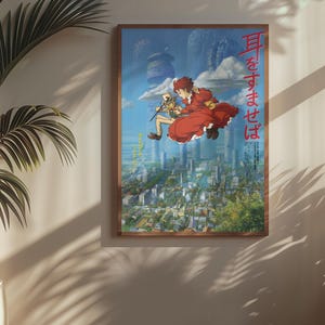 May include: A framed poster featuring a vibrant anime scene. The artwork depicts two figures floating above a cityscape, with one in a red dress. Japanese text is visible on the poster. The frame is a warm brown color.