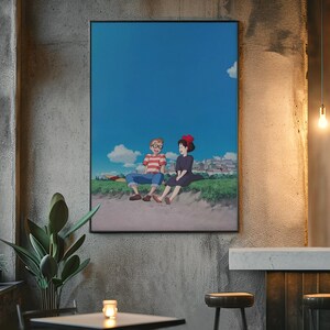 May include: A framed anime art print featuring two characters sitting on a grassy area under a bright blue sky with fluffy white clouds. The artwork is displayed on a textured gray wall.