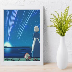 May include: A framed wall art print featuring an illustration of a person with short white hair in a blue dress and a small creature standing on a stone ledge, looking at a night sky filled with bright falling stars above a dark blue body of water.