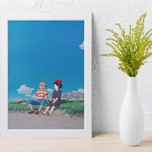 May include: A framed art print featuring an anime-style illustration of two characters sitting on a grassy hill under a bright blue sky with fluffy white clouds. One character wears a red and white striped shirt, the other a black dress.