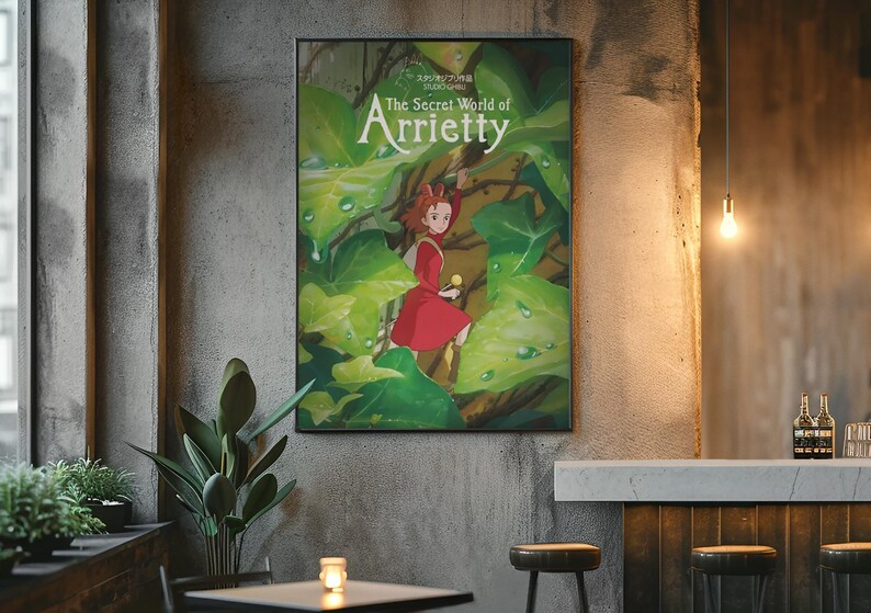 Pu&ograve; includere: Un poster incorniciato di "Arrietty - Il mondo segreto sotto il pavimento" &egrave; appeso a un muro di cemento. L'opera presenta una ragazza in abito rosso tra grandi foglie verdi. Il titolo &egrave; in bianco, con testo giapponese sopra.