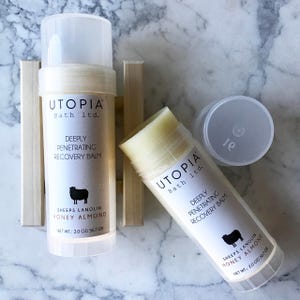 May include: Two white tubes of Utopia Bath Ltd. Deeply Penetrating Recovery Balm with a black sheep logo and the text "Sheeps Lanolin Honey Almond" and "Net Wt: 2.0 oz/56.7 gr".