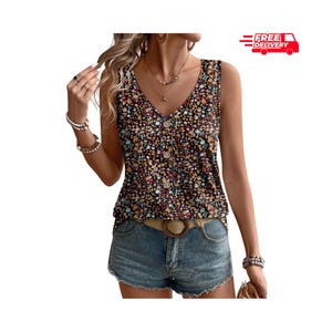 May include: A sleeveless floral print top with a V-neckline and button-down front. The top features a black background with a colorful floral pattern. A brown belt with a circular buckle is visible.