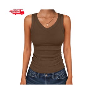 May include: A brown ribbed vest top with a V-neck. The top is worn with blue jeans. A gold necklace with a cross pendant is visible. The image also includes a red and white "FREE DELIVERY" graphic.