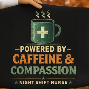 Op de afbeelding: Een zwart stoffen item met een afbeelding van een groene koffiemok met een wit kruis, stoom erboven, en de tekst "POWERED BY CAFFEINE & COMPASSION" in oranje en groen, gevolgd door "NIGHT SHIFT NURSE" met twee kleine groene sterren.