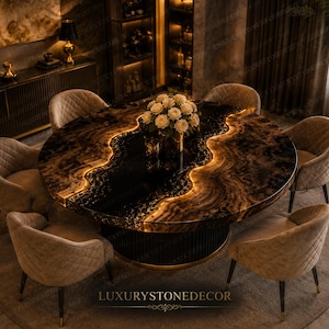 Puede incluir: Una lujosa mesa de comedor redonda con una superficie oscura y estampada y un borde dorado y brillante. Seis sillas tapizadas beige rodean la mesa. Un jarrón con flores blancas está en el centro. El texto "LUXURYSTONEDECOR" está en la parte inferior.
