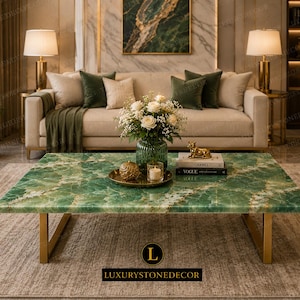 Könnte beinhalten: Ein rechteckiger grüner Stein-Couchtisch mit goldenen Akzenten und goldenen Beinen. Der Tisch befindet sich in einem Wohnzimmer mit einem beigen Sofa, grünen Kissen und einem Blumenarrangement. Das Logo "LUXURYSTONEDECOR" befindet sich unten.