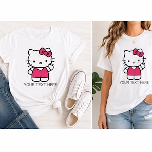 Pode incluir: T-shirt branco com um design de personagem de desenho animado, com la&ccedil;o e vestido rosa, e o texto "YOUR TEXT HERE". O design &eacute; em preto e rosa. A camisa &eacute; combinada com jeans azuis e t&ecirc;nis brancos.