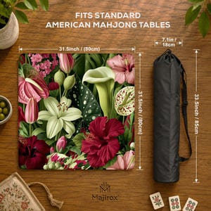 May include: A square mahjong table mat featuring a vibrant floral pattern with pink, red, and white lilies and hibiscus flowers. The mat measures 80 cm by 80 cm and includes a black carrying bag measuring 85 cm by 18 cm.
