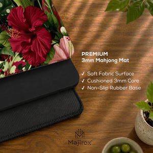 May include: A rectangular mahjong mat featuring a vibrant floral pattern with large red hibiscus flowers and green leaves. The mat has a soft fabric surface, a 3mm cushioned core, and a non-slip rubber base. Text reads: PREMIUM 3mm Mahjong Mat.