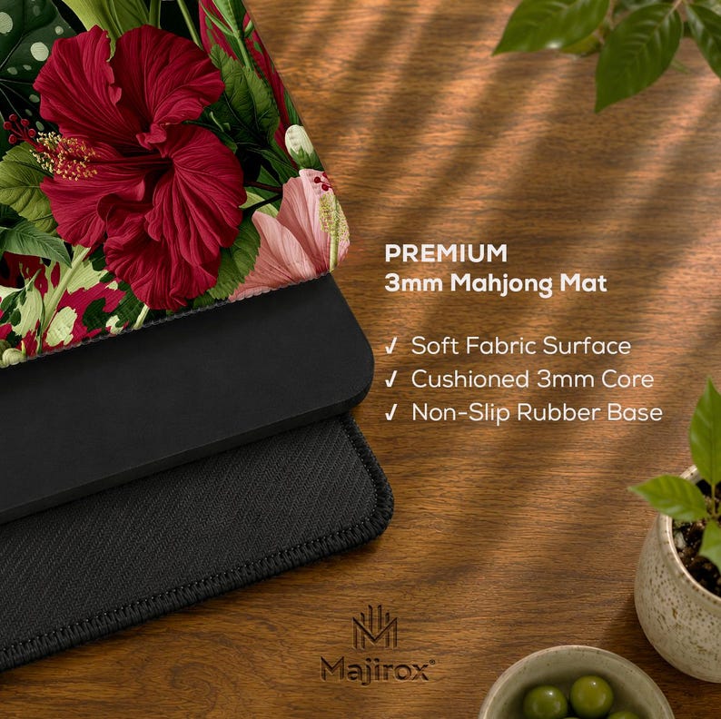 May include: A rectangular mahjong mat featuring a vibrant floral pattern with large red hibiscus flowers and green leaves. The mat has a soft fabric surface, a 3mm cushioned core, and a non-slip rubber base. Text reads: PREMIUM 3mm Mahjong Mat.