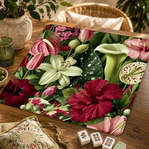 May include: A square mat featuring a vibrant botanical print of deep red hibiscus, pale green calla lilies, white lilies, and pink anthuriums set against a backdrop of dark green foliage with white spots and various flower buds.