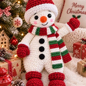 May include: A crocheted snowman doll featuring a white body, three black buttons, and red mittens. It wears a red and white hat with a pom-pom, a red, white, and green striped scarf, and red boots. The snowman has a small orange nose and pink cheeks.