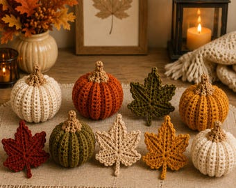 May include: A collection of crocheted pumpkins and maple leaves in various colors including cream, orange, olive green, mustard yellow, and deep red. Each pumpkin features a textured ribbed design with a tan stem, while the leaves are detailed.