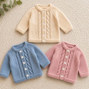 May include: Three long-sleeve knit cardigans in beige, blue, and pink. Each sweater features a round neckline, a vertical cable knit pattern along the button placket, and five white buttons. The garments have ribbed cuffs and a ribbed hem.
