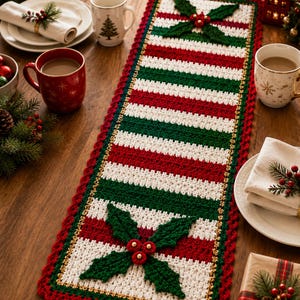 May include: A rectangular crochet table runner featuring alternating horizontal stripes of red, white, and dark green. The runner is bordered by a scalloped red edge and accented with two large, three-dimensional green holly leaf and red berry motifs.