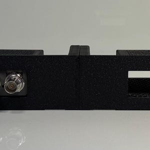 May include: A black rack mount panel with four rectangular openings and three circular connectors. The panel has mounting holes on each end and a raised section in the center. The product is designed for electronic equipment.