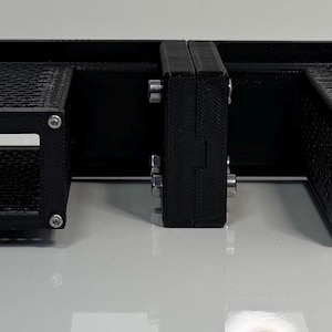 May include: A black rack-mounted server unit with four rectangular compartments. The compartments have a mesh-like design and are mounted on a horizontal metal frame. One compartment has an Ethernet port.