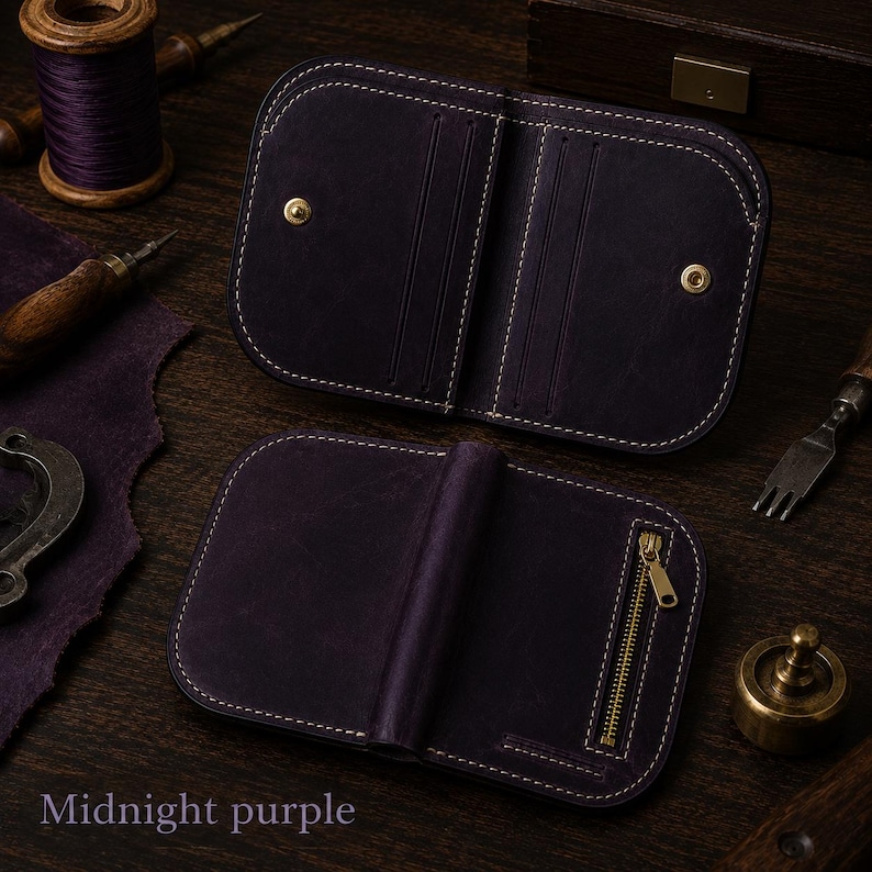 May include: A dark purple leather wallet featuring rounded corners and white stitching. The interior displays card slots and gold-tone snap buttons, while the exterior includes a vertical gold-tone metal zipper. The text Midnight purple is visible.