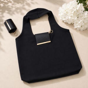 May include: Black tote bag with a matching black wallet and a cylindrical case. The wallet and case have gold-colored metal accents. The tote bag has a loop for carrying and a small pocket with a gold bar.