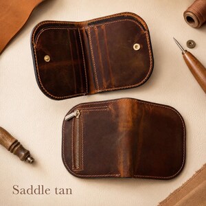 May include: A dark brown leather wallet with rounded edges, featuring an open interior with card slots and a snap closure, and a closed exterior side with a vertical metal zipper pocket. The leather has a distressed finish and visible stitching.