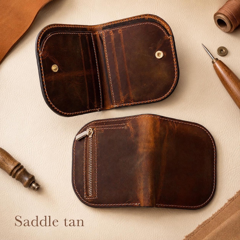 May include: A dark brown leather wallet with rounded edges, featuring an open interior with card slots and a snap closure, and a closed exterior side with a vertical metal zipper pocket. The leather has a distressed finish and visible stitching.