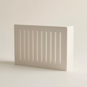 May include: A rectangular off-white wall-mounted storage container featuring a series of vertical, evenly spaced cut-out slots along the front panel. The object has a solid, smooth finish and a clean, boxy structure with a flat top and side.