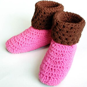 May include: A pair of pink and brown crocheted slippers with a brown cuff. The slippers are made with a simple stitch pattern and have a soft, cozy look.