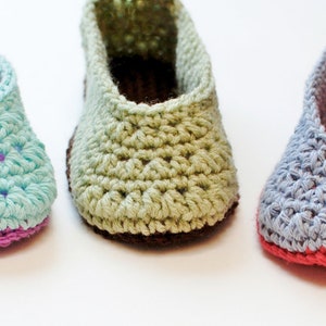 May include: Three pairs of crocheted slippers in different colors. The slippers are made with a simple stitch pattern and have a rounded toe. The colors are light blue, green, and gray.