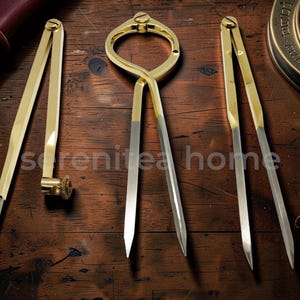 May include: An assortment of antique brass drafting tools, including dividers, a compass, and calipers, displayed on a dark wooden surface. The tools have a polished finish, alongside a vintage compass and leather accessories.