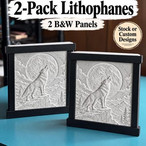 May include: Two square lithophane panels in black frames, each featuring a white relief carving of a wolf howling at a full moon over a mountain landscape. Text on the image reads 2-Pack Lithophanes, 2 B&W Panels, and Stock or Custom Designs.
