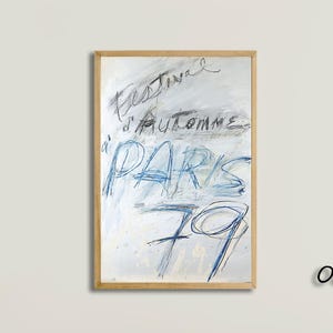 Può includere: Un'opera d'arte astratta in una cornice di legno di quercia chiaro. L'opera presenta le parole "Festival d'Automne PARIS 79" in scrittura blu e nera su sfondo bianco. L'opera è esposta sopra un divano beige.