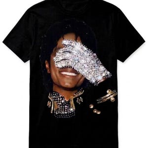 May include: Black t-shirt featuring a portrait of a smiling person with a sparkling glove covering their eyes. The shirt showcases a detailed image of the person's face, jewelry, and a bedazzled glove.