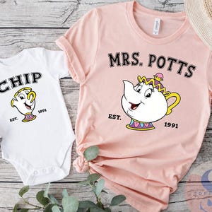 May include: A white baby bodysuit featuring a graphic of Chip with the text CHIP EST. 1991 and a light pink t-shirt featuring a graphic of Mrs. Potts with the text MRS. POTTS EST. 1991. Both garments display colorful cartoon teapot and teacup characters.