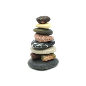 May include: A stack of smooth, colorful stones balanced on top of each other. The stones are various shades of brown, gray, red, and beige.