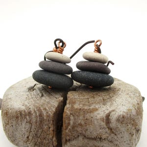May include: A pair of earrings made with stacked stones in shades of gray and white. The stones are held together with copper wire and hang from copper wire hooks.