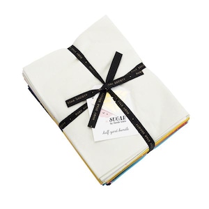 May include: A stack of folded fabric pieces tied with a black ribbon printed with the text Ruby Star Society. A white tag attached to the ribbon features the text Sugar by Sarah Watts and half yard bundle in black and pink lettering.