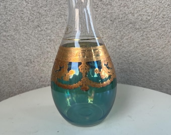 May include: A teal glass vase with gold accents and a gold rim. The vase has a round body and a narrow neck.