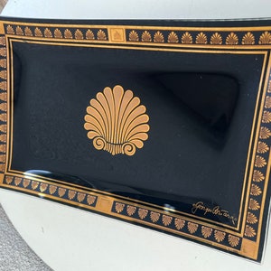May include: A black glass tray with a gold border and a gold seashell design. The tray is signed "George  Berard".