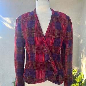 Peut inclure: Un blazer à carreaux rouge, violet et or avec un col en V et une fermeture à bouton.